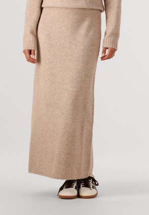 Beige maxirok van een wolmix met een geribbelde tailleband en zoom; gecombineerd met bruine en crème sneakers met veters en rubberen zolen.