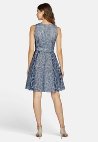 Blaues Spitzenkleid mit ärmellosem Design, tailliertem Schnitt und ausgestelltem Rock. Verfügt über filigrane florale Muster und eine glatte Textur.