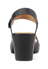 Sandal con tacco a cuneo nero, con tomaia in pelle liscia, cinturino alla caviglia regolabile e soletta contornata color tan. Retro chiuso con suola in gomma testurizzata.