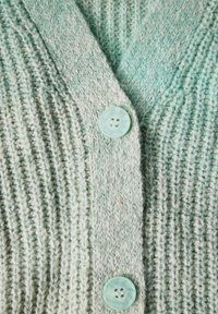 Ljusgrön stickad kofta med ribbat mönster, som har två runda, ljusgröna knappar vid halsringningen.