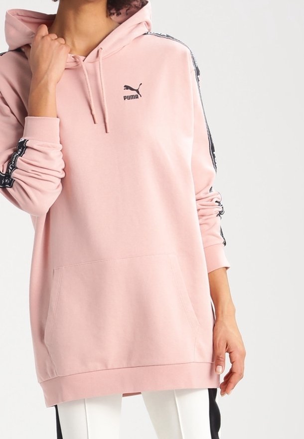 Rosa hoodie i mjukt tyg, med en känguruficka, huva och svarta sidor med ränder samt en logotyp på bröstet.