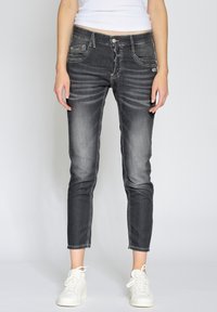 Smala mörkgråjeans med blekta detaljer, fem fickor och dragkedja. Matchas med vita sneakers. Slät denimtextur.