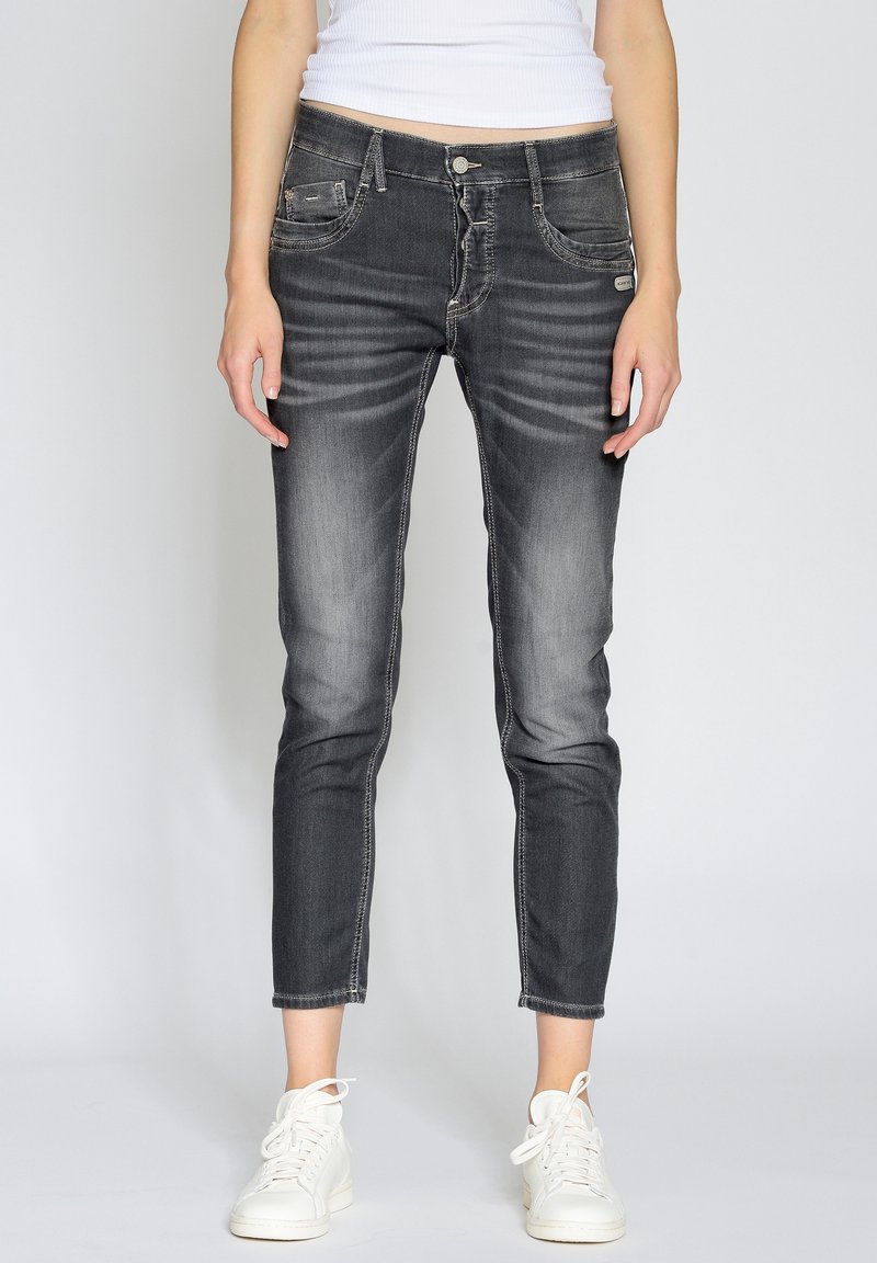 Smala mörkgråjeans med blekta detaljer, fem fickor och dragkedja. Matchas med vita sneakers. Slät denimtextur.