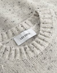 Pull en tricot gris clair avec un col côtelé, texture mouchetée et une étiquette indiquant "LES DEUX". Matériau en mélange de laine doux.