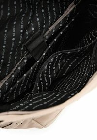 Interiér tašky VUCH je černý textil s bílým potiskem a puntíky. Obsahuje více přihrádek, kapsu na zip a hladkou texturu.