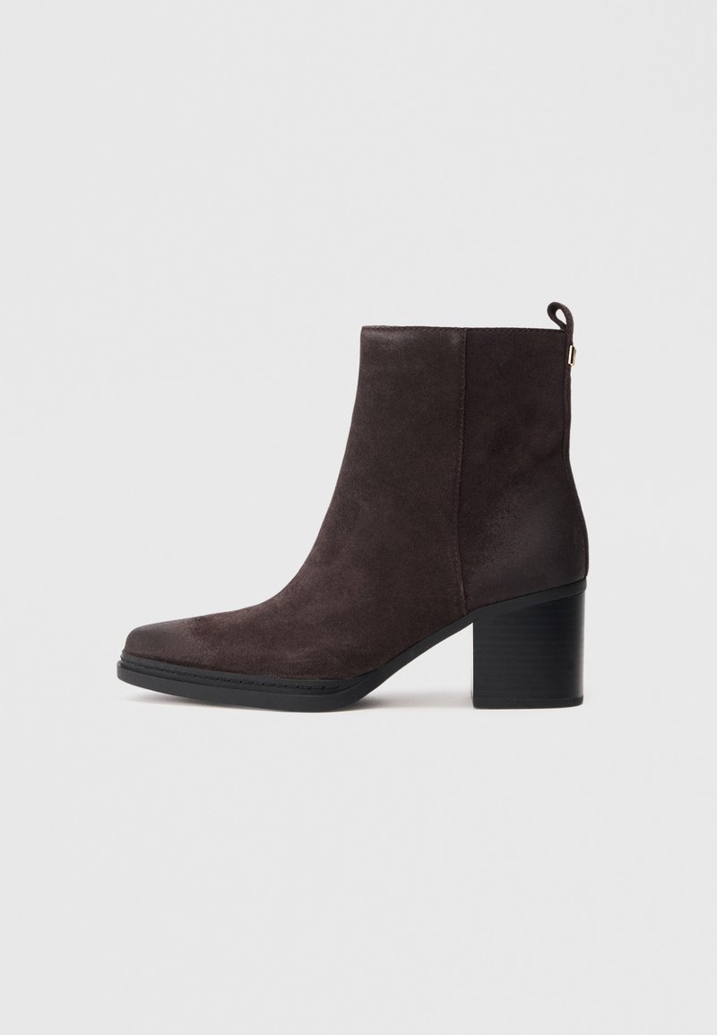 Stivaletto in camoscio marrone con punta quadrata, tacco medio e linguetta sul retro; presenta una suola nera liscia e cuciture sottili.