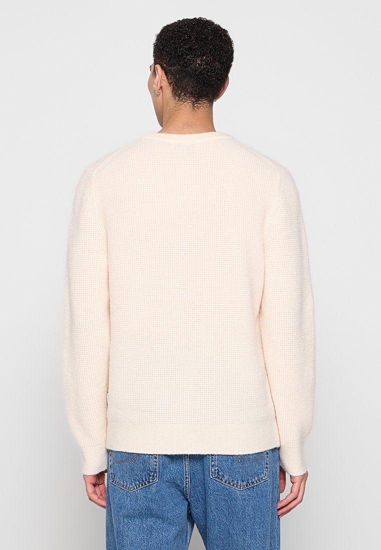 Hellbeige gestrickter Pullover mit einem strukturierten Waffelmuster. Verfügt über lange Ärmel und einen runden Ausschnitt, am Ende mit einem geraden Saum abgeschlossen.