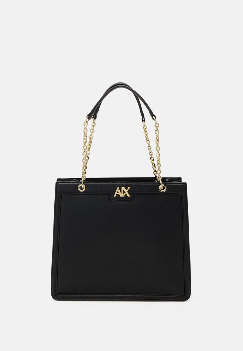 Bolso tote negro sintético con asas de cadena en tono dorado, con un detalle de logo en la parte frontal y superficie de textura suave.