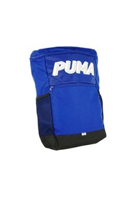 Modrý látkový batoh s veľkým bielym logom "PUMA", čiernym dnom, bočnou sieťovanou kapsou a vrchným zipsom.
