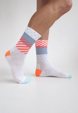 Bunte Crew-Socken mit einem weißen Grundton, die blaue Punkten, rote Streifen und lebendige orange Akzente an den Zehen und Fersen aufweisen.