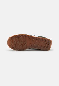 Trail shoes with a brown rubber sole featuring aggressive traction lugs, black, gray, and white panels, and reinforced toe cap.