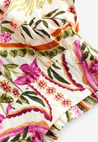 Blomstertextil med mönster i rosa, lila och orange på en ljus bakgrund; inkluderar rynkade kanter med lätt textur.