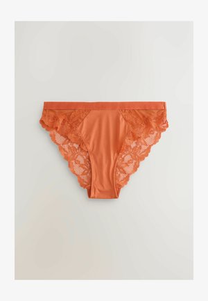 Oranssit bikinimalliset alushousut, joissa on sileä etupaneeli ja kukallinen pitsikoristelu sivuilla ja takana, sekä aaltoilevat reunat.