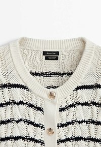 Cardigan en coton blanc tricoté avec des rayures horizontales noires, des boutons décoratifs dorés et un col rond côtelé.