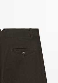 Vue arrière d'un pantalon marron foncé montrant une poche passepoilée boutonnée unique et un passant de ceinture à la taille.