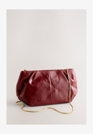 Vīna sarkanas ādas rokas soma ar krokotu dizainu, zelta ķēdes siksniņu un strukturētu formu, ar gludu un spīdīgu tekstūru.