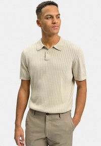 Beige randig polo-tröja med krage, korta ärmar och knappslå, tillsammans med ljusbruna byxor som har en slät yta.