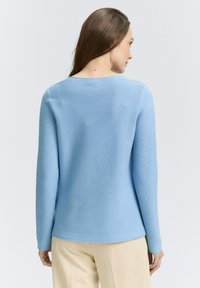 Pull léger bleu clair �à manches longues avec une texture côtelée, un col ras du cou et un ourlet droit. Présente une finition lisse et un minimum de détails.