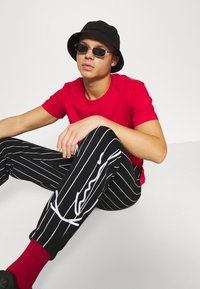 Karl Kani SIGNATURE PINSTRIPE PANTS UNISEX - Treniņtērpa apakšdaļas - black