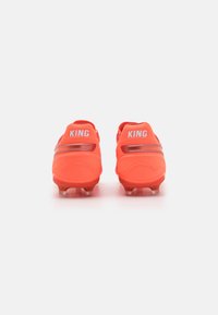 Bright orange soccer cleats with a textured surface, featuring white "KING" logos, and a streamlined design with sturdy studs for grip.