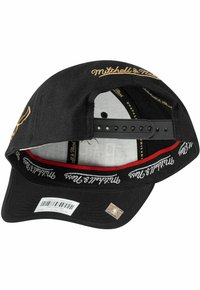 Black baseball cap with a curved brim, featuring gold embroidery and a red accent inside. Adjustable snapback closure at the rear.