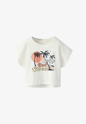 Camiseta blanca recortada con palmeras, pájaros, atardecer y texto "Salty But Sweet" en estilo vintage en el frente.