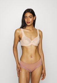 Beha en broekje set in nude en blush tinten, met kantafwerking, een gaaspaneel op de beha, brede banden en een zachte stof.