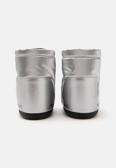 Paire de bottines argentées brillantes avec semelles noires vues de dos sur fond blanc.