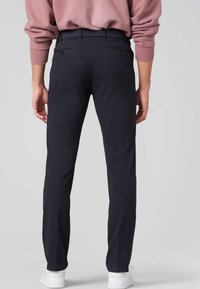 Svart, skreddersydde bukser med rett passform, med et teksturert belte og sidelommer, kombinert med hvite joggesko.