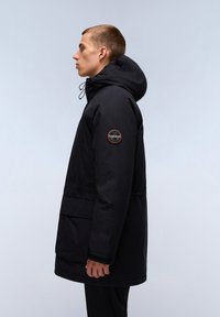 Zwarte parka met capuchon, voorzien van een ritssluiting aan de voorkant, een trekkoord en zijzakken. Inclusief een ronde logo patch op de linkermouw.