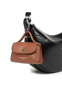 Small brown leather bag with silver button attached to black crescent-shaped leather bag by metal clasp.