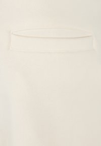 Tela color crema con textura suave, que presenta un pequeño bolsillo horizontal con un borde cosido. Diseño minimalista y sencillo.
