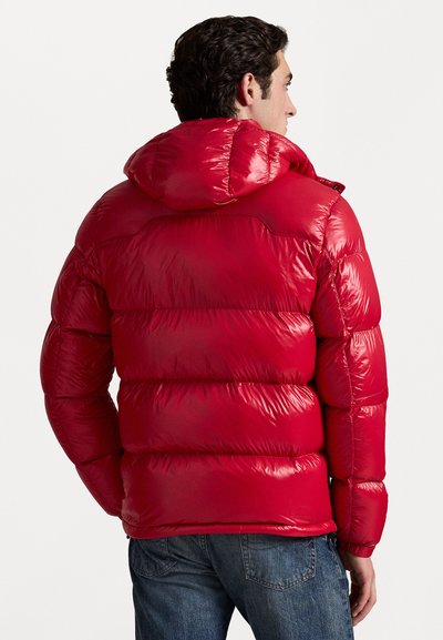 Rød puffjakke med en skinnende, quiltet overflade og hætte. Designet har horisontale syninger og elastiske manchetter.