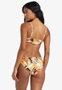 Bikini set with a multicolored abstract pattern in shades of orange, pink, brown, and green. Strappy top with a simple hook closure.