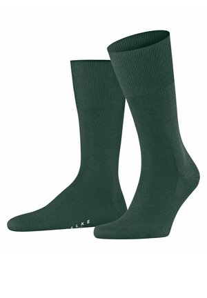 Dunkelgrüne Baumwollsocken mit einem gerippten Bündchen, glatter Textur und verstärktem Zehenbereich. Markenname auf der Seite sichtbar. Klassische Knöchellänge.
