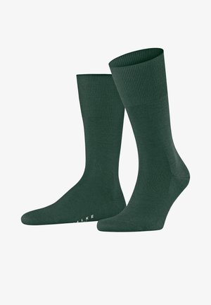 Dunkelgrüne Baumwollsocken mit einem gerippten Bündchen, glatter Textur und verstärktem Zehenbereich. Markenname auf der Seite sichtbar. Klassische Knöchellänge.