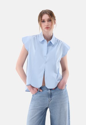 Camicia azzurra chiara a maniche corte con chiusura a bottoni e colletto a punta; tessuto liscio con sottili pieghe lungo le spalle.