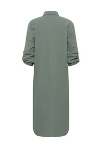Robe chemise verte longue, col à boutons, manches longues retroussées aux coudes, texture douce, ourlet incurvé, design simple, sans motifs ni accents visibles.
