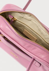 Ροζ δερμάτινη τσάντα χειρός με χρυσά μεταλλικά στοιχεία και φερμουάρ. Το εσωτερικό διαθέτει μπεζ επένδυση και ετικέτα με το λογότυπο της μάρκας. Συμπαγές σχέδιο με διπλά διαμερίσματα.