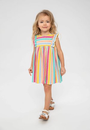 Robe rayée colorée avec de courtes manches froncées en rose, bleu, jaune et vert. Une paire de sandales blanches avec un accent floral.