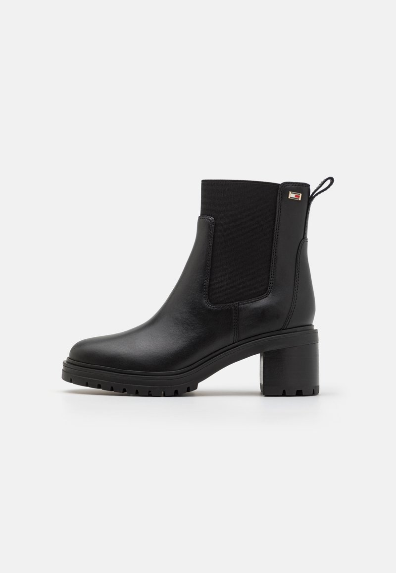 Bottine en cuir noir avec talon carré, panneau latéral élastique, languette de tirage et petit logo rectangulaire près du bord supérieur.
