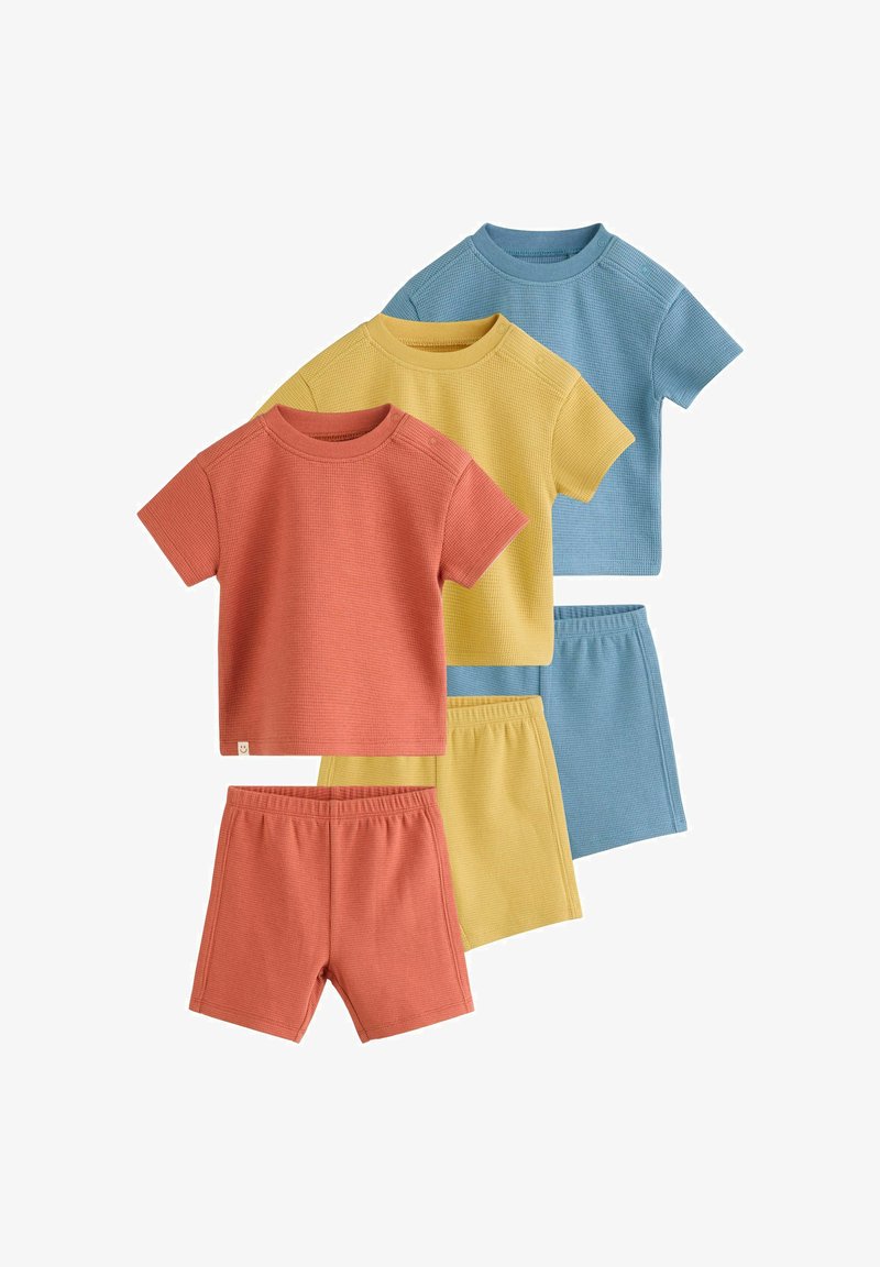 Trois ensembles de hauts à manches courtes et shorts pour enfants à texture gaufrée, dans des couleurs orange, jaune et bleu, disposés en chevauchement.