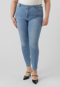 Lyseblå skinny jeans med høyt liv, med klassisk fem-lomme design, subtil falming, og parret med svarte spisse heels.