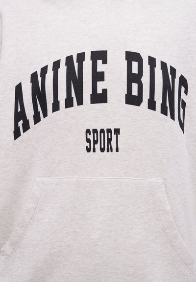 Gray sweatshirt with front pocket featuring black text "ANINE BING" arched above smaller text "SPORT" centered on the chest.