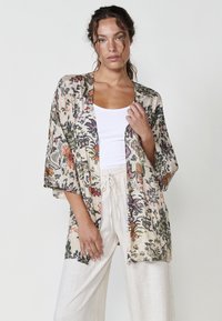 Kimono con estampado floral hecho de tela ligera, que presenta un corte relajado, frente abierto y mangas anchas en tonos crema, verde y rojo.