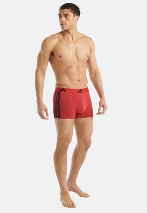 Rode sportieve shorts met zwarte strepen, gemaakt van rekbaar materiaal. Kenmerkt zich door een aansluitend ontwerp en een naadloze tailleband voor comfort.