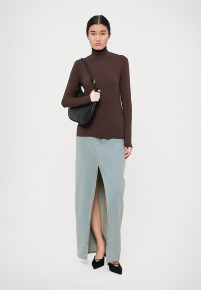 Brown turtleneck top, light blue denim maxi skirt with front slit, black woven handbag, and black pointed heels.