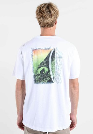 Homme portant un t-shirt blanc avec un graphisme coloré de surf et le mot "OXBOW" dans le dos, vu de dos sur fond blanc.