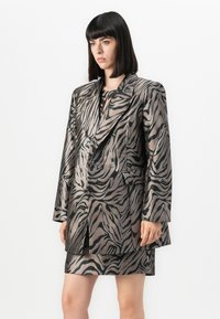 Grå og svart metallisk blazer- og skjørtsett med sebramønster. Blazeren har en notch-lapel, overdimensjonert design og frontlommer.