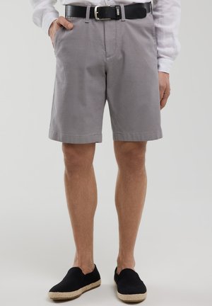 Gray shorts made of woven fabric, featuring a flat front, side pockets, and a smooth finish. Paired with black slip-on shoes.